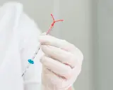 Mano enguantada sostiene un DIU de tamaño pequeño, listo para su inserción.