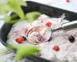 Glace au yaourt italienne aux fruits rouges, servie dans un bac avec une cuillère. Parfait pour une recette facile et rafraîchissante.
