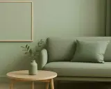 Salon paisible avec canapé et table basse, le tout dans une douce **couleur vert sauge**. Un cadre vide attend d'être rempli.