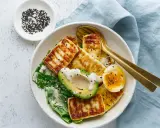 Szybki keto obiad: grillowany ser halloumi, awokado, jajko na miękko i zielone liście, posypane sezamem.