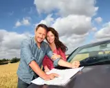 Para planują podróż, sprawdzając mapę przy samochodzie. Pewni siebie, wiedzą, że nawet w razie problemów za granicą, assistance zadba o nich.