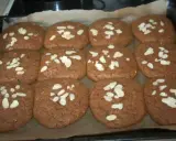 Douze biscuits faits maison, parfaits pour une recette speculoos, garnis d'amandes effilées sur une plaque de cuisson.