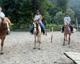 Tre donne si godono una passeggiata a cavallo in Lombardia, con un uomo che le osserva.