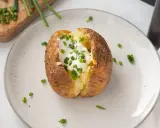 Patatas asadas en freidora de aire, crujientes por fuera, tiernas por dentro, coronadas con crema agria y cebollino fresco.