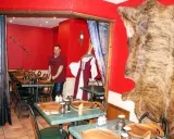 Un homme se tient dans un restaurant moyen âge décoré d'une peau d'ours et d'une épée.