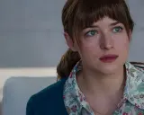 Dakota Johnson med sina blå ögon och blonda hår, klädd i en blommig skjorta och en mörkblå kofta. En scen från filmer med Dakota Johnson.
