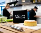 Idealny biszkopt czeka na włożenie do nagrzanego piekarnika. Obok trzepaczka i tabliczka "Biszkopt Idealoy".