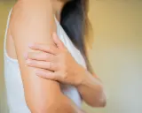 Une femme se gratte le bras, évoquant les démangeaisons cutanées liées à la ménopause.
