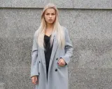 Blondynka w szarym płaszczu i czarnej koronkowej bluzce. Czerń to klasyczny wybór, jaki kolor pasuje do szarego ubrania, dodając elegancji.
