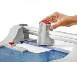 Mano operando una guillotina o cizalla para cortar papel con precisión.