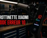 Trottinette Xiaomi avec code erreur E10 affiché sur l'écran. L'atelier de réparation est visible en arrière-plan.