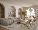 Przytulny salon z pufiastą sofą i plecionymi fotelami. Ciepłe odcienie bieli dominują w aranżacji, tworząc spokojną atmosferę.