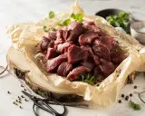 Pokrojone w kostkę mięso na gulasz z dzika, ułożone na papierze, gotowe do przyrządzenia.
