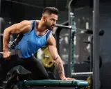 Mann beim **bodybuilding training** im Fitnessstudio, der mit einer Hantel rudert.