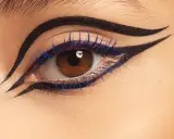 Ojo con delineado dramático y pestañas azules, inspirado en el maquillaje egipcio.