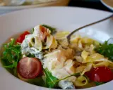 En krämig laxpasta med spenat, körsbärstomater och ruccola. En gaffel lyfter upp en bit av den läckra pastan.
