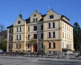 Ustroń rynek: reprezentacyjny budynek ratusza z charakterystyczną wieżyczką i zegarem, otoczony ławkami i stolikami kawiarnianymi.