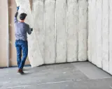 Hombre instala aislamiento en pared ya construida. Proceso de como aislar una pared.