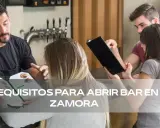 Un camarero muestra un menú a clientes. Quizás planean abrir un bar en Zamora, como si tuvieran el carnet A.