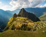 Un lama pasta en la cima de una montaña, contemplando la majestuosidad de que es Machu Picchu, una ciudadela inca entre picos andinos.