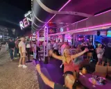 Nachts auf der Albufeira Partymeile: Menschen tanzen und feiern unter Neonlicht in Bars und Clubs.