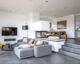 Modernes Split-Level-Haus mit offenem Wohnbereich, Kamin, Essbereich und Küche. Ein Kater döst auf dem Sofa.