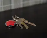 Nycklar med en röd Verisure-tagg. Tänk på hur larmar man på Verisure när du lämnar hemmet.