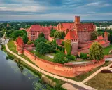 Potężny zamek w Malborku, jedna z największych atrakcji Polski, otoczony murami obronnymi i rzeką Nogat.