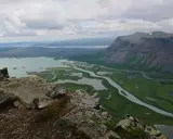 Vacker utsikt över Rapadalen med Skierfe i bakgrunden. En slingrande flod flyter genom ett grönt landskap med sjöar.