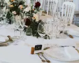 Un élégant dressage d'une table à la française, prêt pour un festin. Verrerie étincelante, fleurs fraîches et menus attendent les convives.
