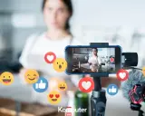 Kobieta nagrywa filmik w kuchni, a wokół telefonu unoszą się emotikony. Idealne do aplikacji do oglądania filmów i tworzenia treści.