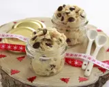 Två glasburkar fyllda med chokladbitsdeg, perfekt för ett enkelt cookie dough recept. Dekorerat med julband och små granar.
