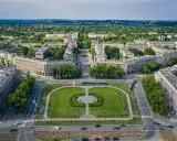 Plac Centralny w Nowej Hucie z socrealistyczną zabudową, zielonymi skwerami i torami tramwajowymi.