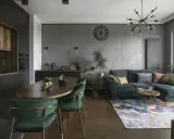 Nowoczesny czarny salon z drewnem, zielona kanapa, owalny stół i designerska lampa.