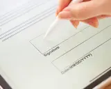 Mano firmando un contrato de arrendamiento digitalmente en una tableta con un lápiz óptico.