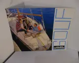 Une famille profite d'une journée ensoleillée à bord d'un voilier Golif. Le bateau est amarré, et ils semblent planifier leur prochaine aventure nautique.