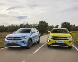 Un Volkswagen T-Cross azul y un T-Roc amarillo circulan por una carretera rural.