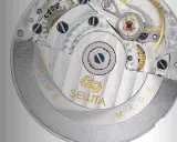 Dettaglio del movimento Sellita, con ingranaggi e finiture di precisione. La scritta "SWISS MADE" circonda il meccanismo.