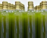 Botellas alineadas llenas de un líquido verde vibrante, reflejando el color del aceite de oliva virgen extra.