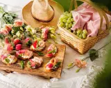 En härlig picknick med jordgubbsbruschetta, vindruvor i korg och blommor på en **picnic mat**.