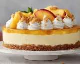 Eine köstliche Solero Torte mit Pfirsichspalten, Sahnetuffs und Streuseln auf einem Keksboden.