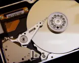 Vue rapprochée de l'intérieur d'un disque dur de PC, montrant le plateau, la tête de lecture/écriture et le moteur. L'emplacement du disque dur est essentiel pour le stockage des données.