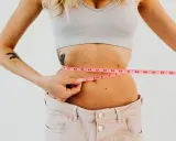Kobieta mierzy talię centymetrem. Efekty diety 1400 kcal są widoczne.