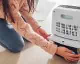 Persona extrae el depósito de agua de un deshumidificador para que sirve, manteniendo el aire seco y saludable en casa.
