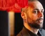 Ardalan Esmaili, med ansiktet belyst av ett randigt ljus, tittar bort.