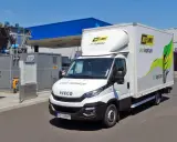 Biała ciężarówka Iveco zasilana gazem CNG, z logo "NO LIMIT eko logistyka", zaparkowana przy stacji paliw.
