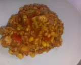 Pyszne kaszotto z kurczakiem, kukurydzą i pomidorami na białym talerzu.