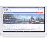 Tablet wyświetla stronę EDB - Elektroniczny Dziennik Budowy. Pracownicy w kaskach pracują na budowie.
