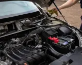 Silnik samochodu z widocznym akumulatorem i elementami układu dolotowego. Czy to zepsuty alternator czy akumulator?