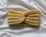 Żółta, skręcona opaska na drutach z grubym splotem. Wzory opasek na drutach mogą być tak proste i eleganckie.